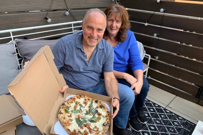 a person holding a box of pizza