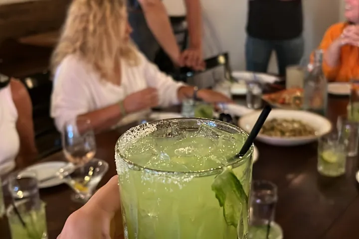 a group of people sitting at a table with food and drinks